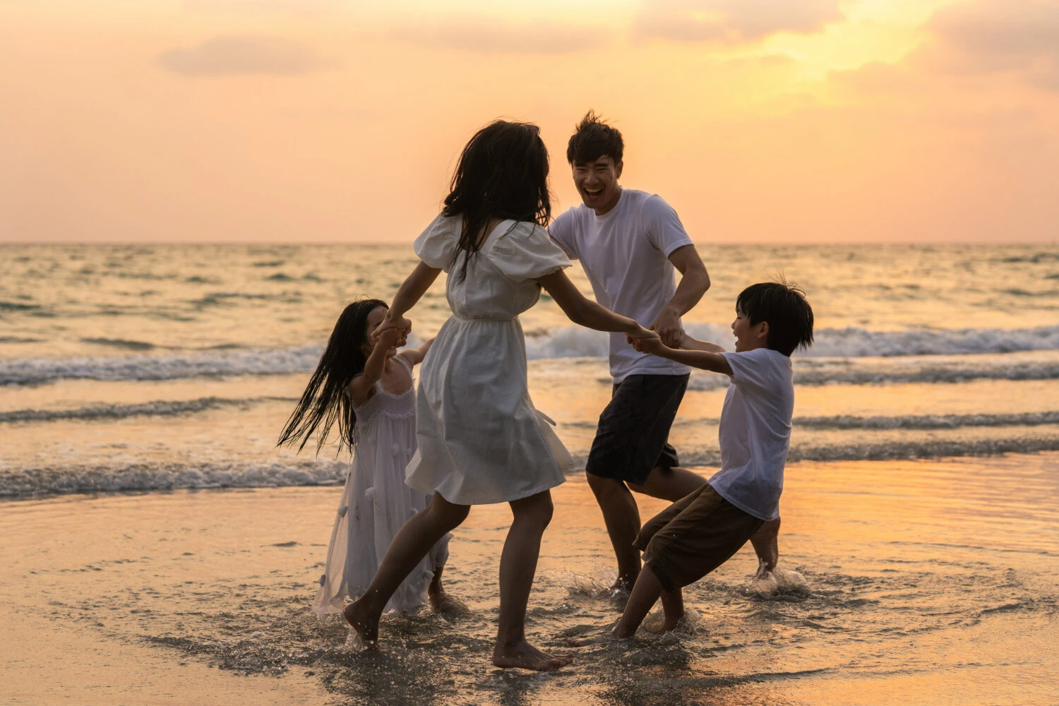 Janeiro branco. Viajar em família para destinos com praia faz bem à saúde mental. Pesquisas apontam que Planejar viagem torna pessoas mais felizes. Fotografia de família feliz se divertindo na praia, ao pôr do sol. Imagem de tirachardz.